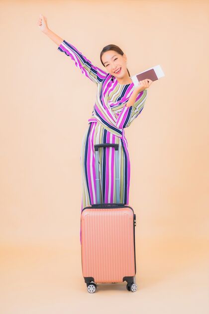 放松肖像美丽的亚洲年轻女子带着行李护照和登机牌准备彩色旅行女性包时间
