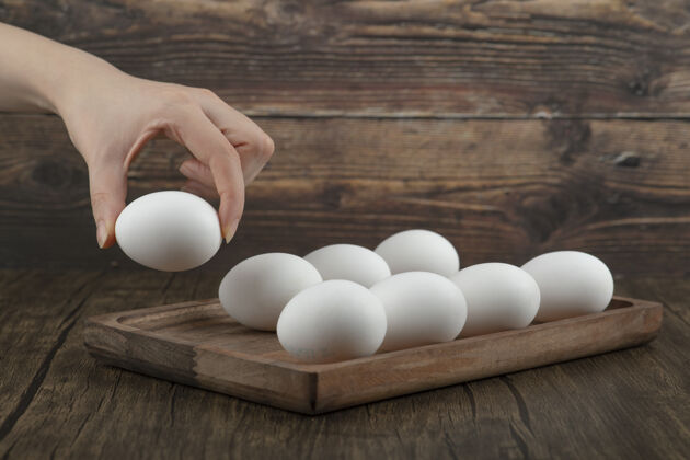 人雄性从木板上拿生的有机鸡蛋烹饪木材食物