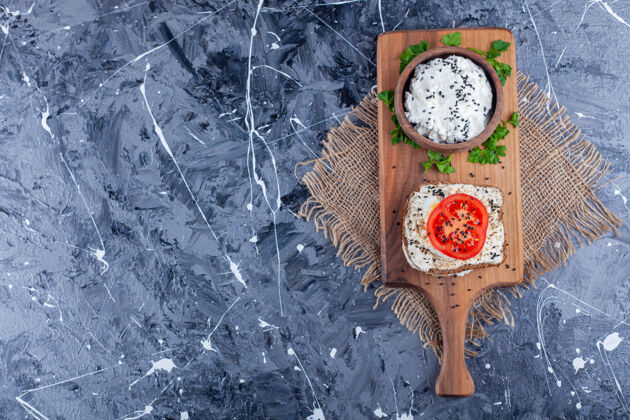 面粉一碗芝士旁边的西红柿片上放着芝士面包 放在切菜板上的粗麻布餐巾上 蓝色的美味番茄酵母