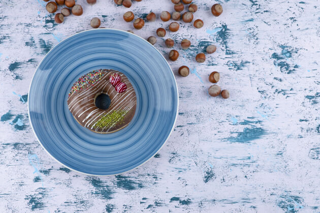 浆果蓝色盘子 白色表面有巧克力甜甜圈和带壳榛子蛋糕贝壳面包房