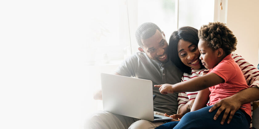 父亲快乐的黑人家庭和幼儿指着笔记本电脑屏幕设计空间男人沙发一起