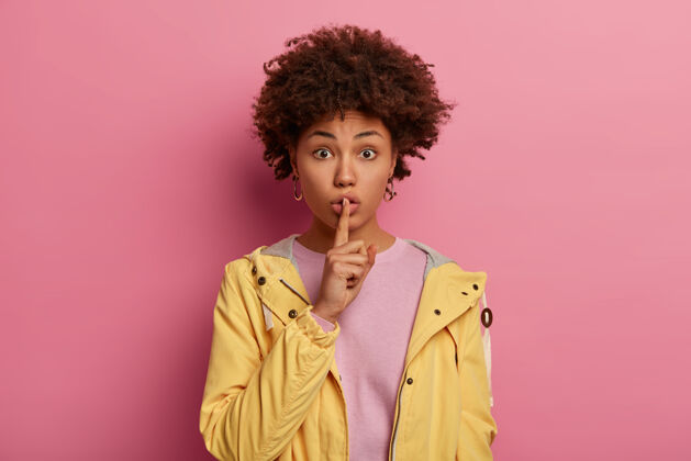 安静非裔美国妇女的照片 把食指放在嘴唇上 讲秘密信息 谈论同事 做安静的手势 穿着黄色的休闲服黑发手势手指