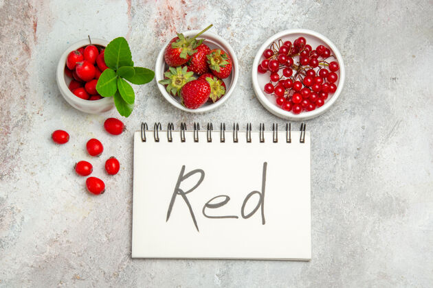 饮食顶视红色水果与红色书写记事本上的白色表浆果红色水果记事本健康成熟
