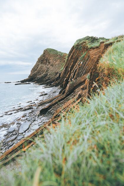 悬崖在白天 在蓝色的海边 悬崖上长满了绿草海景叶天