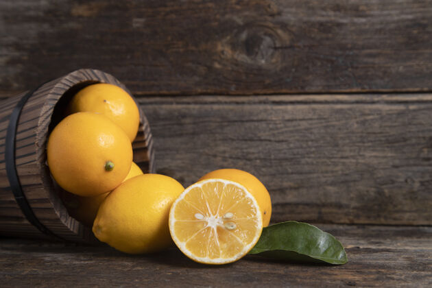 多汁一个木制的篮子里装满了新鲜的柠檬水果 叶子放在一张木制的桌子上高质量的照片柠檬素食柑橘