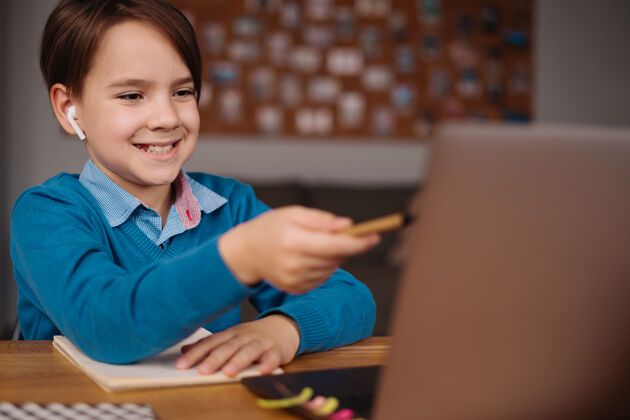 技术一个未成年男孩用笔记本电脑在线上课笔记本电脑耳机沟通