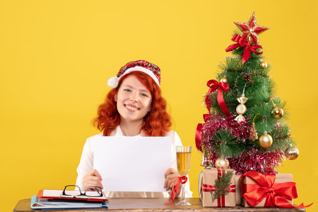 色彩正面图女医生拿着文件和礼物坐在桌子后面情感节日圣诞