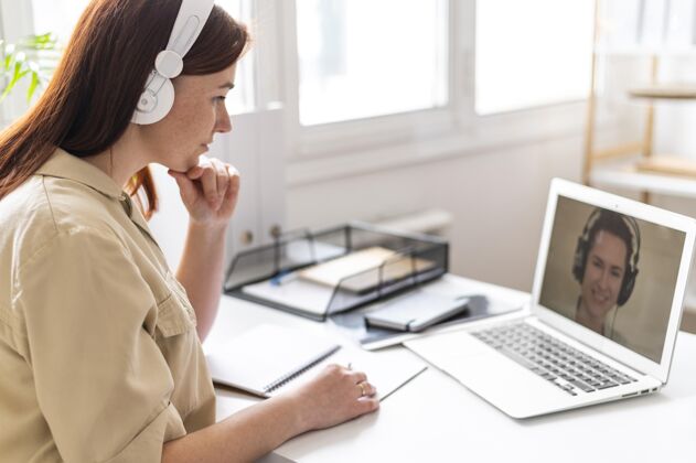 耳机工作中的女人正在笔记本电脑上进行视频通话模型办公室笔记本电脑