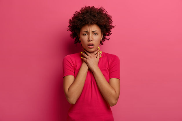 窒息不高兴的黑皮肤女人有哮喘发作 呼吸不好 手放在脖子上 皱眉头 窒息或窒息 咳嗽 有健康问题 穿着休闲服 隔离在粉红色室内阴性
