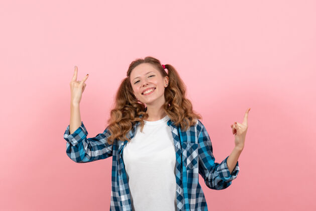 格子正面图穿着格子衬衫的年轻女性在浅粉色背景上摆姿势年轻女性彩色情感模特儿成人微笑青年