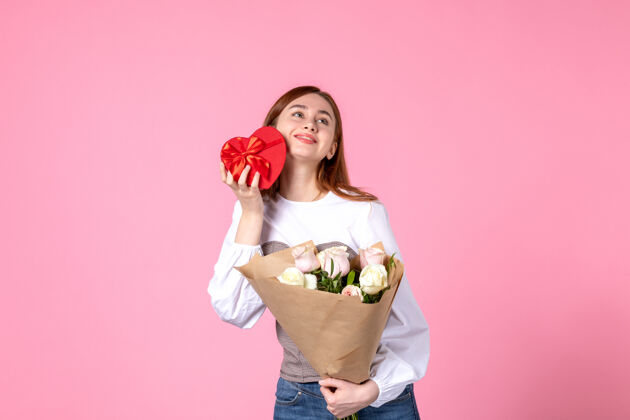 花正面图：年轻女性 带鲜花 在粉色背景上作为妇女节礼物 水平三月平等 女性约会 玫瑰色 女人爱感性礼物人年轻女性