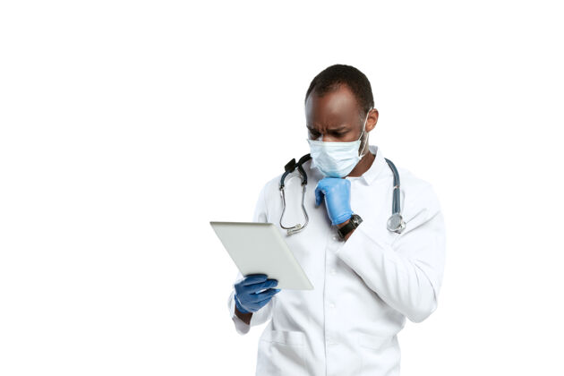 病毒悲伤的阅读新闻男年轻医生带着听诊器和口罩在白色工作室严肃器械医疗