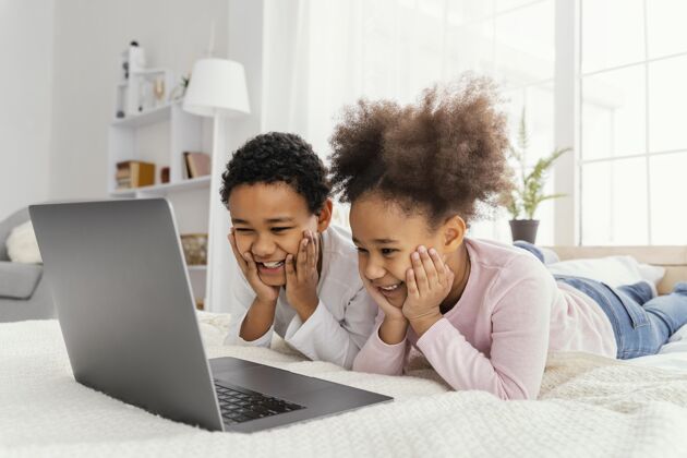 内部两个兄弟姐妹在家一起玩笔记本电脑水平团结乐趣