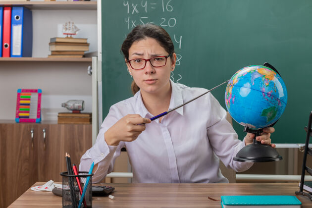 指针年轻的女老师戴着眼镜拿着地球仪指着表情地球仪女人