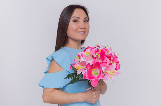 花束站在白色的墙上 一位亚洲妇女手持花束 面带微笑 喜气洋洋地庆祝国际妇女节站立举办国际