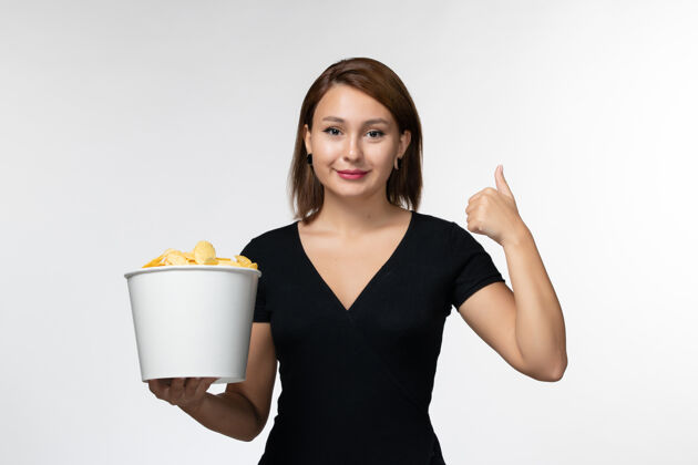 漂亮正面图：年轻的女性拿着土豆片篮子 微笑着站在白色的表面上土豆女士电影