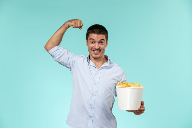 电影正面图年轻的男性拿着土豆片篮子 在蓝色的表面上弯曲电影院剧院举行