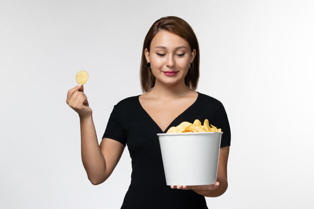 篮子正面图：白色表面上放着薯片的年轻女性手提篮年轻的女性电影院土豆