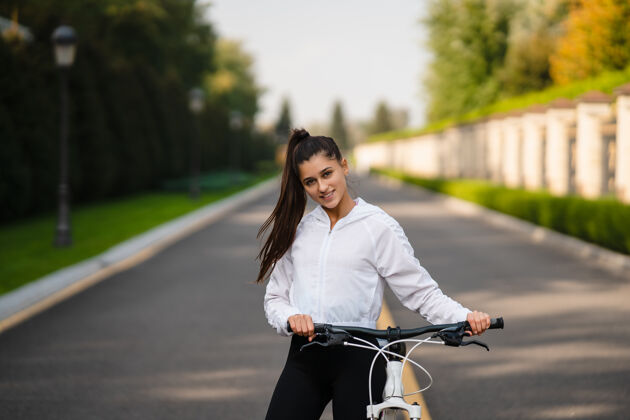 自然美丽的女孩在白色自行车前摆姿势在大自然中行走健康的生活方式微笑美丽公园