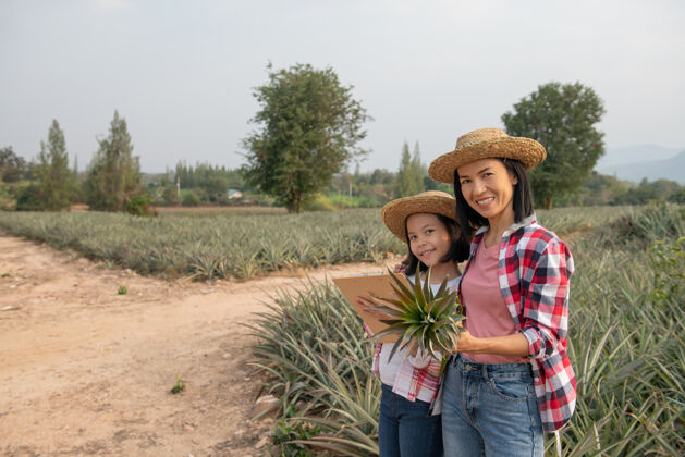 孩子亚洲农民让母亲和女儿在农场里看到菠萝的生长情况 并把数据保存在她的剪贴板上给农民核对清单家庭女人检查