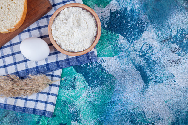美味面包片放在煮鸡蛋旁边 一碗面粉放在蓝色毛巾上酵母面包美味
