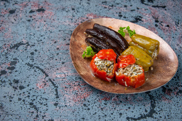 菜前视图茄子与煮熟的西红柿和甜椒与肉末填充在蓝色背景板内多尔玛胡椒粉食物番茄
