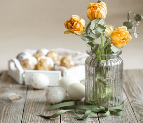 郁金香一束鲜花放在一个玻璃花瓶里 在模糊的背景上有装饰元素复活节假期的概念复活节彩蛋节日传统