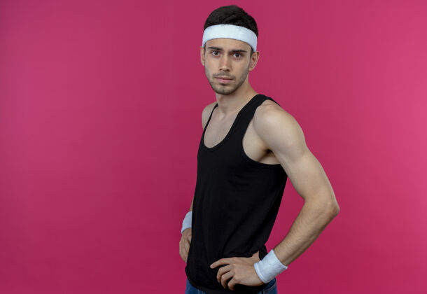 粉色戴着头巾的年轻运动型男子 自信严肃的表情 手臂放在臀部 粉色以上自信严肃男人