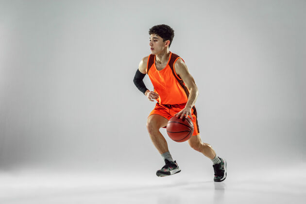 运动年轻的篮球队员穿着运动服训练 在运动中练习 在奔跑中运动 隔离在白墙上运动的概念 运动 活力和活力 健康的生活方式射击运动小伙子