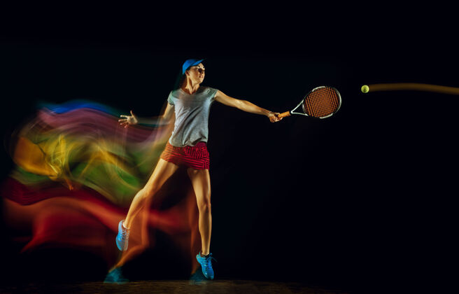 跑步一位白人女子在黑色的墙壁上打网球 在混合和淡色的灯光下适合年轻的女性运动员在运动比赛中运动或行动运动的概念 运动 健康的生活方式玩室内切割