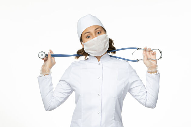 疾病正面图女医生穿着白色医疗服 戴着无菌口罩 在白墙上进行大流行性疾病药物病毒隔离面罩成人男性