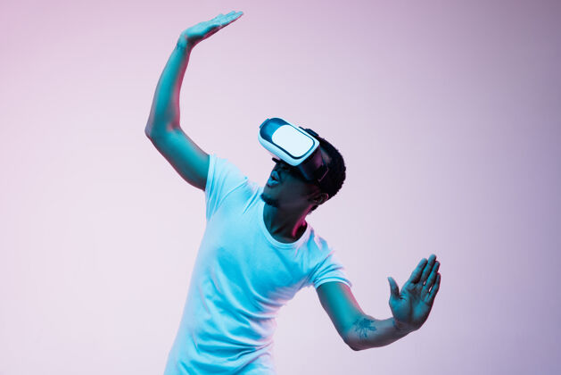 游戏年轻的非洲裔美国男子的发挥和使用虚拟现实眼镜霓虹灯梯度背景非洲表情合成