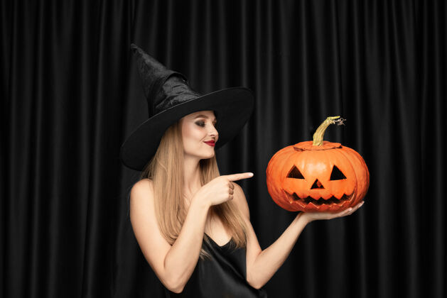 巫师年轻的金发女郎 戴着黑色帽子 穿着黑色背景的服装迷人 性感的女模特万圣节 黑色星期五 网络星期一 销售 秋天女杰克金发