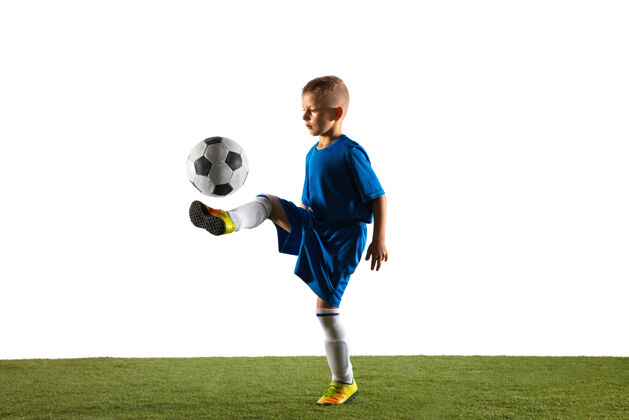 比赛穿着运动服的足球运动员或足球运动员的小男孩 为了在白色场地上进球而用球假装或踢活力比赛跑步