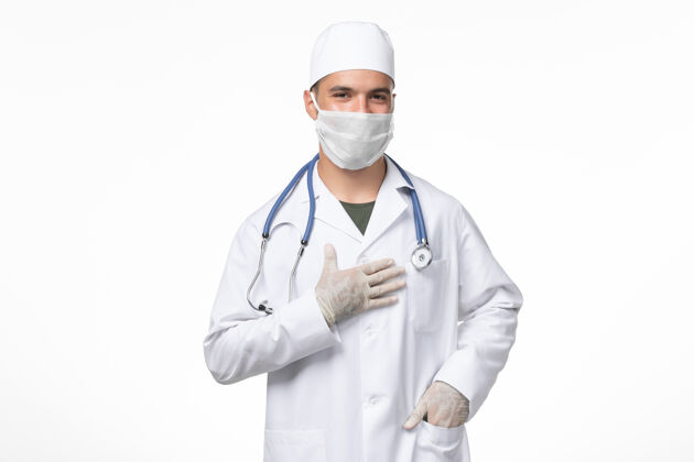 医生正面图：男医生穿着医疗服 戴着防毒面具 在浅白的墙壁上对抗冠状病毒病的药物大流行专业听诊器口罩