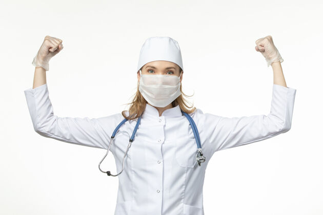 浅白色前视图：女医生穿着医疗服 戴着口罩和手套 因为冠状病毒和弯曲的白墙疾病流行性冠状病毒医疗正面医生