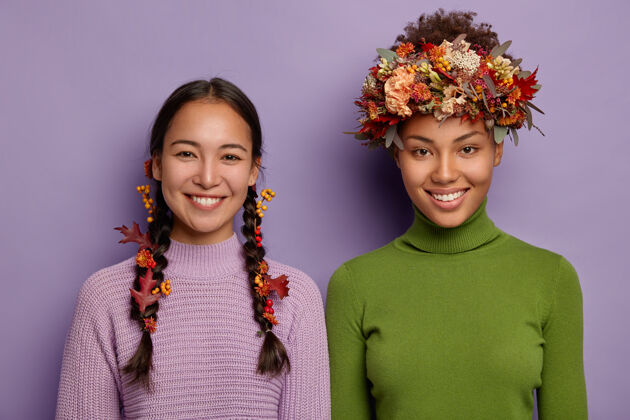 紫色喜洋洋的混血女画像 穿着暖和的衣服 头发上点缀着秋叶 表达美好的情感 站在彼此旁边亚洲辫子女孩