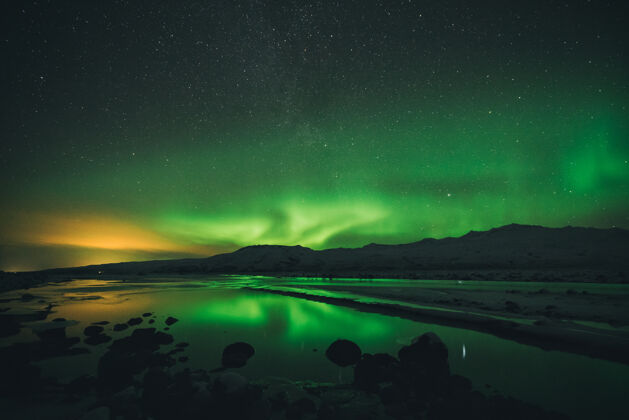 冰岛夜晚北极光下 山边的水很平静自然极光户外