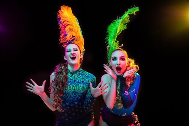 面具美丽的年轻女子在狂欢节和化装舞会服装在五颜六色的霓虹灯在黑墙上年轻女人格拉斯