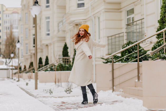 兴奋在下雪的街道上走着 兴奋的姜女回头看一个迷人的红发白衣女人的户外镜头冷杉户外城市