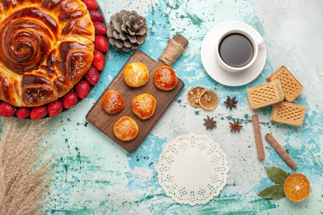 饼干俯瞰圆形美味的馅饼 新鲜的红色草莓蛋糕和一杯茶在蓝色的表面桌子早餐派