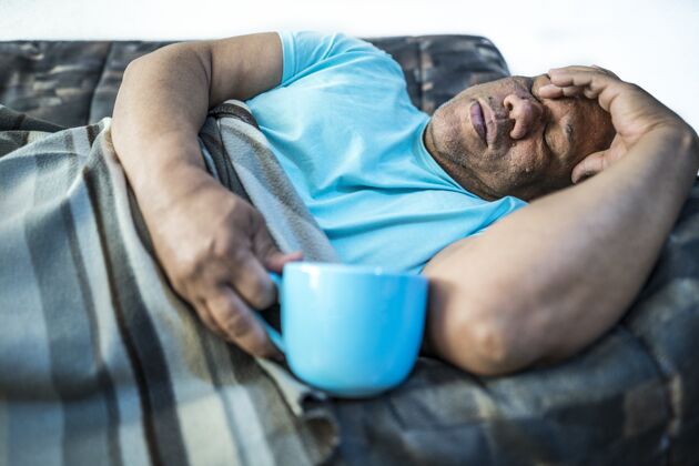 脂肪一个男人拿着蓝色杯子躺在沙发上的照片面部形状皮肤