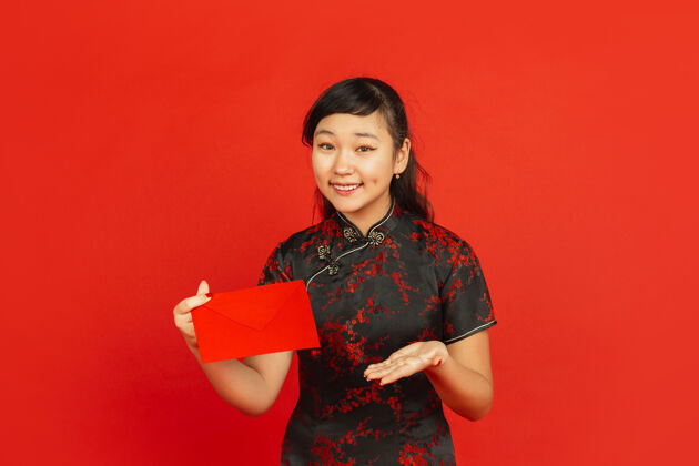 信封中国新年红色背景上孤立的亚洲少女肖像身着传统服装的女模特看起来很开心 微笑着 拿着红包庆祝 节日 情感旗袍红色新年