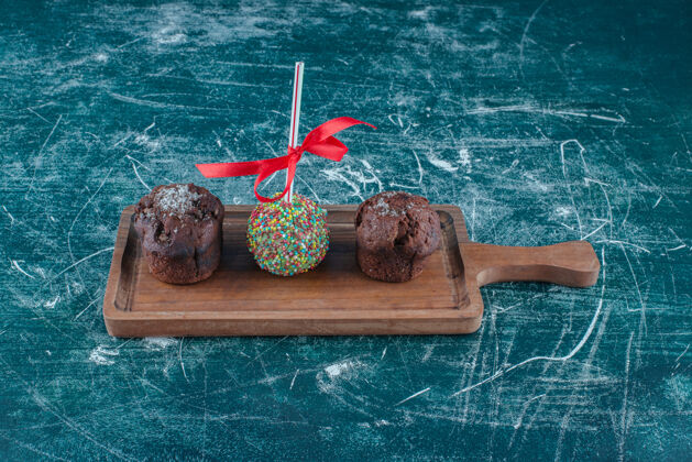 巧克力巧克力纸杯蛋糕和糖果包棒棒糖在蓝色背景板上高质量的照片口感外套烘焙