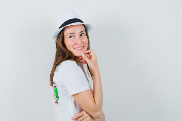成人年轻女子一边回想 一边穿着白色t恤 戴着帽子 看上去很乐观帽子可爱欢呼
