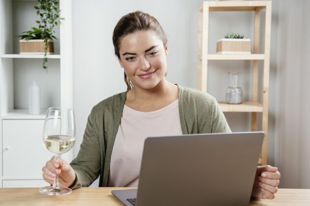 在线流女人拿着一杯酒用笔记本电脑房子笔记本电脑设备