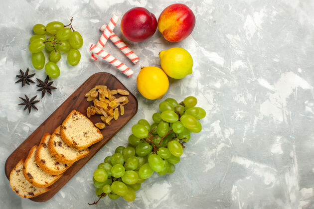 新鲜在浅白色的桌子上俯瞰新鲜的绿色葡萄和葡萄干以及蛋糕片醇香柠檬葡萄