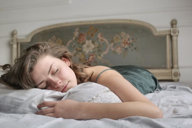 床年轻的女人早上在床上安详地睡觉房子美丽自然