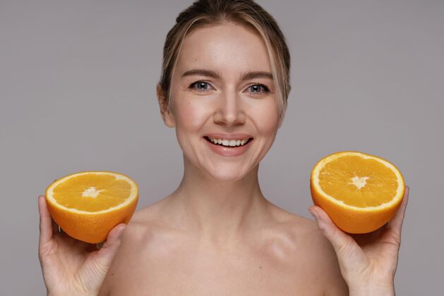 人拿着一半橘子的漂亮女人模特自我护理清透肌肤