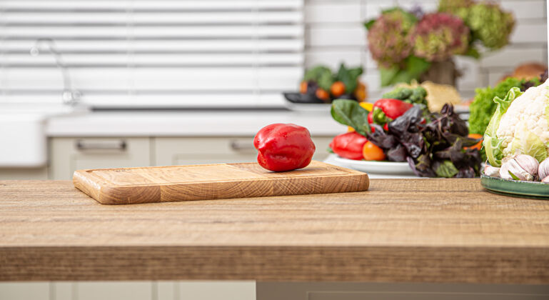 膳食新鲜的红甜椒放在木板上 背景是厨房内部准备素食饮食